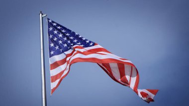 Mavi gökyüzü ve beyaz bulut önünde dalgalanan büyük Amerikan bayrağına yakın çekim. Amerikan Bayrak Dalgası. Amerikan bayrağının dalgalanmasını kapat
