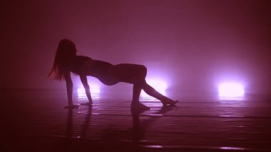 Genç, havalı bir kadın, kulüpte ışıklarla erotik danslar yapıyor.
