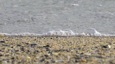 Deniz kenarındaki çakıl taşları. Mavi denizin ipeksi dalgaları
