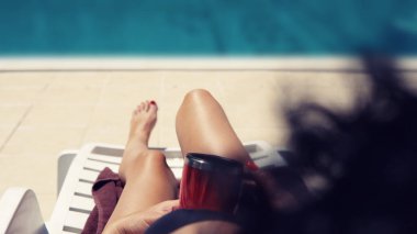 Havuz kenarında kahve içip bronzlaşan seksi kız.