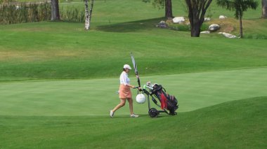 Bansko, Bulgaria - 12 Sep, 2019: Smiling man pushing his clubs on self driving cart on a golf course