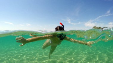 Su yüzeyinde şnorkelle yüzen genç bir kızın ardından, Gopro Dome yarı su altı manzarası