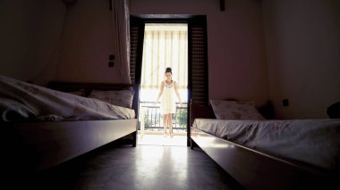 Siluet kadın yatak odasında perdeyi açıyor ve sabah kalktıktan sonra uzanıyor.