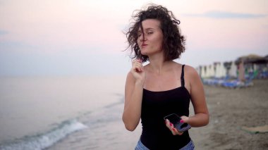 Gün batımında güneşli sahilde dans eden tatlı kız.