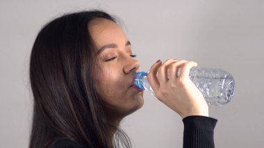 Genç bayan bir şişe su içiyor.