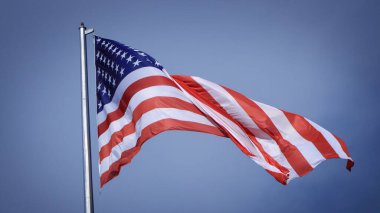 Mavi gökyüzü ve beyaz bulut önünde dalgalanan büyük Amerikan bayrağına yakın çekim. Amerikan Bayrak Dalgası. Amerikan bayrağının dalgalanmasını kapat