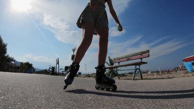 Deniz kenarında güneşli bir günde etekli paten kayan bir genç.