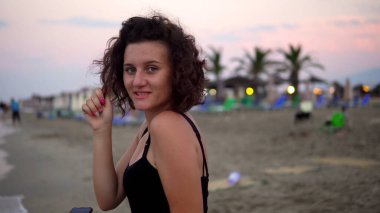 Gün batımında güneşli sahilde dans eden tatlı kız.