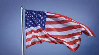 Mavi gökyüzü ve beyaz bulut önünde dalgalanan büyük Amerikan bayrağına yakın çekim. Amerikan Bayrak Dalgası. Amerikan bayrağının dalgalanmasını kapat