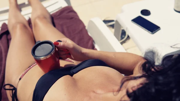 游泳池边的性感女孩一边喝咖啡一边晒太阳 — 图库照片