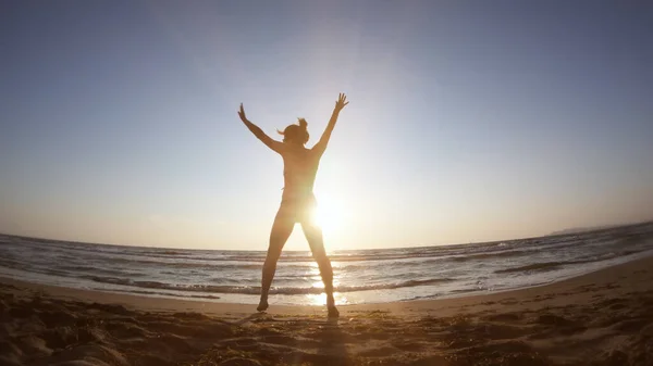 日落时在海滨做体操锻炼的健康妇女 — 图库照片