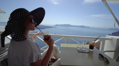 Fira, Santorini manzaralı lüks otel kafesinde yaz tatilinin tadını çıkaran mutlu bir kadın. Avrupa 'ya seyahat. Turist yaşam tarzı.