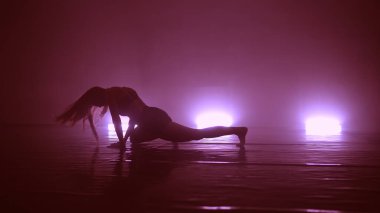 Genç, havalı bir kadın, kulüpte ışıklarla erotik danslar yapıyor.