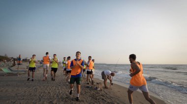 Durres, Arnavutluk - Ağustos 2017: Futbol takımı gün doğumunda denizde koşu antrenmanına katıldı. Deniz kıyısında bir tur atıyorlar. buharlı çekim