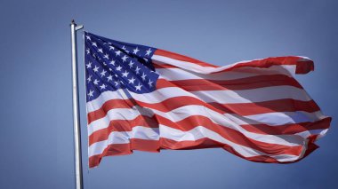 Mavi gökyüzü ve beyaz bulut önünde dalgalanan büyük Amerikan bayrağına yakın çekim. Amerikan Bayrak Dalgası. Amerikan bayrağının dalgalanmasını kapat