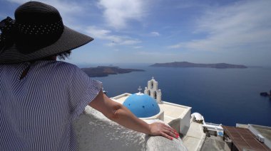 Fira, Santorini, Yunanistan 'daki Fira kilisesinin üç çanı yakınında gülümseyen mutlu esmer kadın.