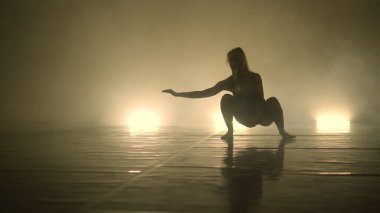 Dansçı kadın, karanlık ışıklı odada gösteri yapıyor.