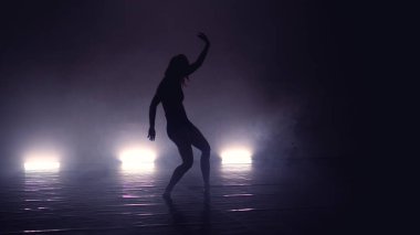 Genç, güzel, çağdaş balerin dumanlı sahnede modern bale yapıyor.