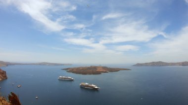 Fira, Santorini 'nin çatıları üzerinde panoramik çekim. Kameni volkanı adasına demir atmış feribot botları, el kamerasıyla çekilmiş.