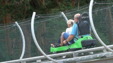 Bansko, Bulgaristan - 20 Ağustos 2019: Erkek ve kız yaz eğlence treni yolculuğunun tadını çıkarıyorlar. Kırmızı bir lunaparkta heyecanlı bir yolculuktan zevk alırken komik bir ifadeleri vardır.