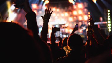 İnsanlar akıllı telefondan şarkıcıların konserini kaydediyor.