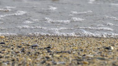 Deniz kenarındaki çakıl taşları. Mavi denizin ipeksi dalgaları