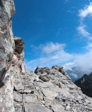 Olymp, Yunanistan - 22 Temmuz 2018: Dağcı kayalık zirveden tehlikeli bir şekilde düştü Mytikas 'ın en yüksek Olimpiyat zirvesi, aşırı tırmanma, dikey yönelim