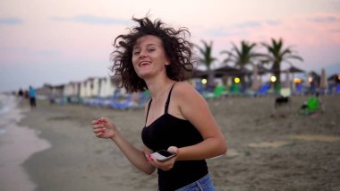 Gün batımında güneşli sahilde dans eden tatlı kız.