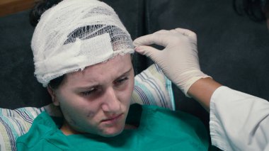 Doktor kafasında travma ve elastik bandajla bir hastanın kafasına dokunuyor. 