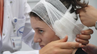 Doktor kulak ameliyatından sonra klinikteki baş hastaya bandaj yapıyor.