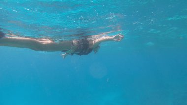Mısır 'da tropik bir adada bikinili bir kadın su altında şnorkelle yüzüyor.