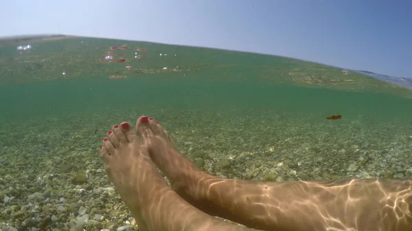 海の浅い水の中に浮かぶ女性の足 夏休みのコンセプト 半分水中ビューGoproドームショットリラックス — ストック写真