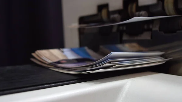 Closeup of printing a pile of paper photo pictures at copy center, print enlargements