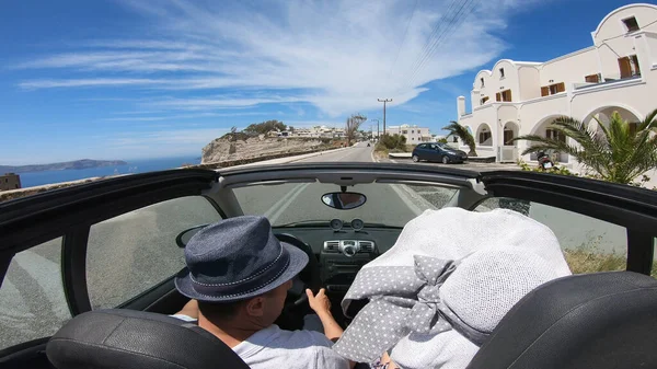 Couple on road trip driving by the coast, Santorini Island, Greece