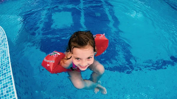 Ευτυχισμένο Κοριτσάκι Φουσκωτά Μπρατσάκια Χαλαρώνοντας Στην Πισίνα Χαμογελώντας — Φωτογραφία Αρχείου