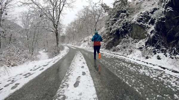 Młody Zdrowy Sportowiec Biegnie Asfaltowej Drodze Śnieżnej Górskiej Drodze — Zdjęcie stockowe