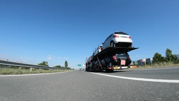 大型トラック 車の輸送業者は 高速道路を走行する中古車を提供します — ストック写真