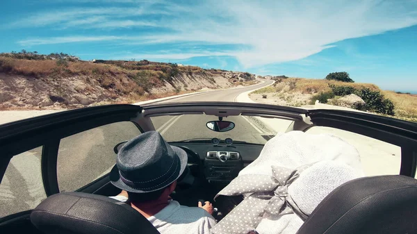 Couple on road trip driving by the coast, Santorini Island, Greece