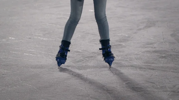 Legs of Young woman skating on ice ring