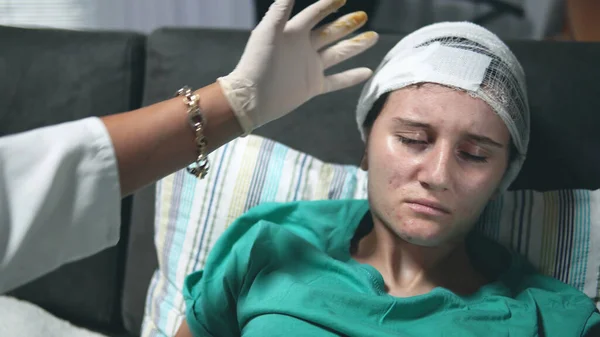 医生检查躺在病床上的头戴绷带的年轻妇女的头部 — 图库照片
