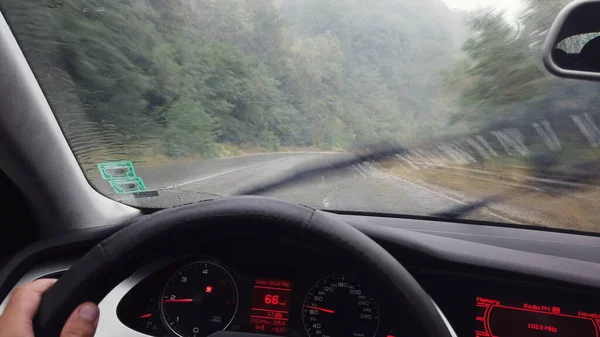 山のアスファルトの道路を運転雨滴と車のフロントガラスを介して運転Pov — ストック写真