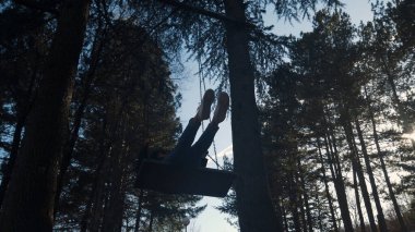 Güzel esmer ağaçta sallanıyor, ormanda sallanıyor, ağır çekimde.