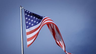 Mavi gökyüzü ve beyaz bulut önünde dalgalanan büyük Amerikan bayrağına yakın çekim. Amerikan Bayrak Dalgası. Amerikan bayrağının dalgalanmasını kapat