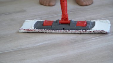 Çıplak ayaklı kadın ıslak mendille yerleri temizliyor.