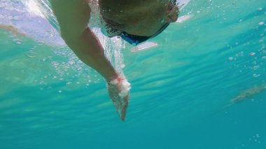 Genç adam denizde sürünüyor, sualtı manzaralı.