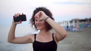 Gün batımında güneşli sahilde dans eden tatlı kız.