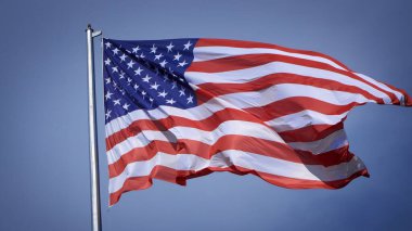 Mavi gökyüzü ve beyaz bulut önünde dalgalanan büyük Amerikan bayrağına yakın çekim. Amerikan Bayrak Dalgası. Amerikan bayrağının dalgalanmasını kapat
