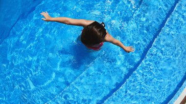 Yüzme havuzuna atlayan heyecanlı küçük kız. Mutlu yaz tatilleri.