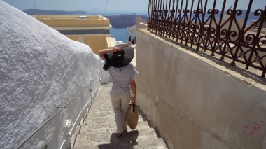 Fira, Santorini 'nin merdivenlerinde zarif bir kadın yürüyor.