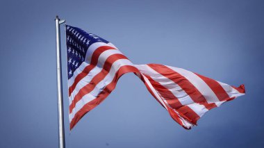 Mavi gökyüzü ve beyaz bulut önünde dalgalanan büyük Amerikan bayrağına yakın çekim. Amerikan Bayrak Dalgası. Amerikan bayrağının dalgalanmasını kapat